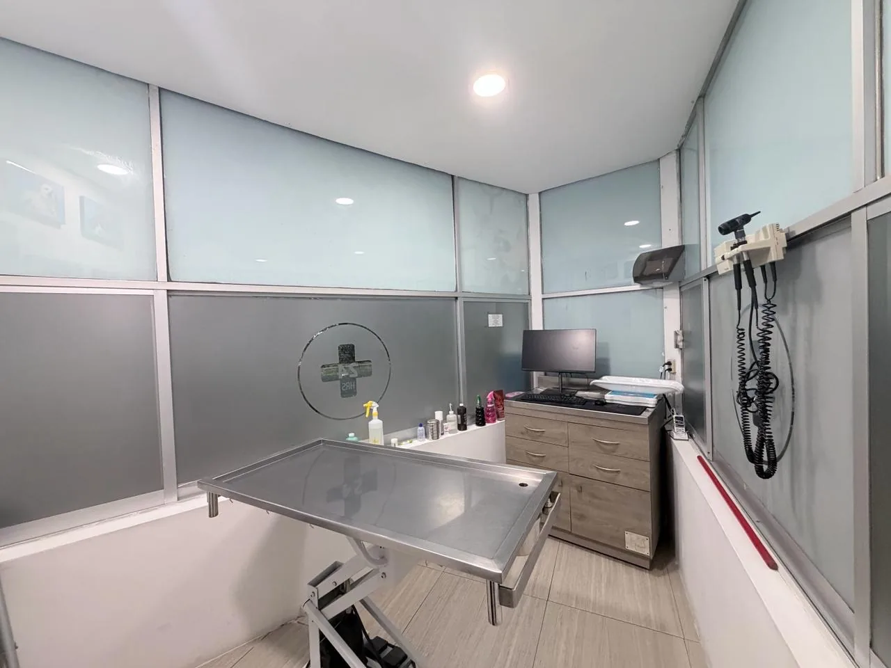 Consultorio con mesa de exploración hidráulica, computadora y otoscopio de pared