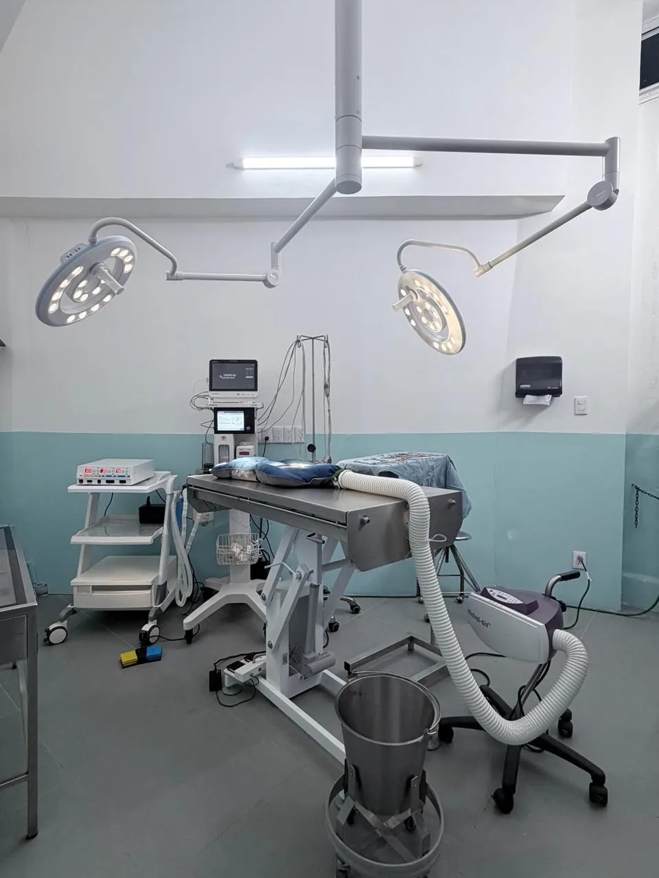 Quirófano con dos lámparas quirúrgicas, mesa de cirugía, monitor de signos vitales y máquina de anestesia