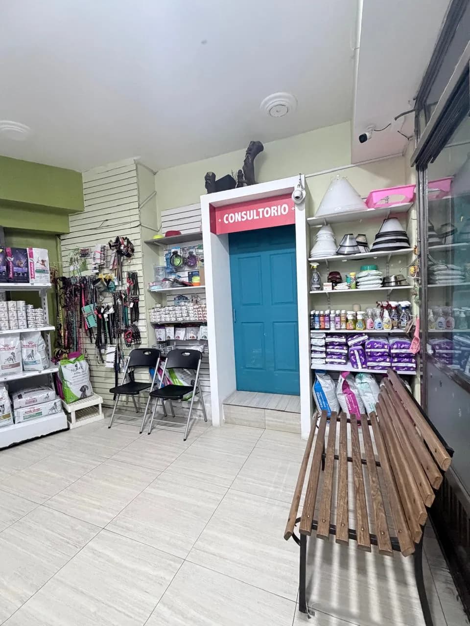 Zona de espera con sillas y banca de madera junto a la puerta del consultorio
